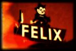 A vintage neon sign features a smiling cartoon cat character named "Felix" above large illuminated letters spelling "FELIX." The sign has a warm, nostalgic glow with reddish-orange hues in the background.