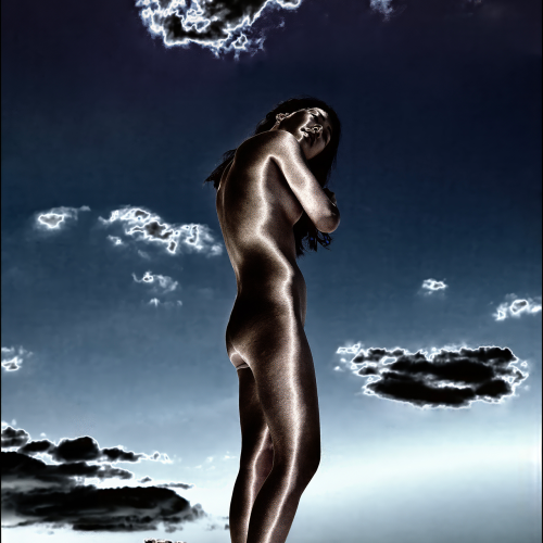 A person standing on a ledge against a dark, inverted-color sky with clouds.