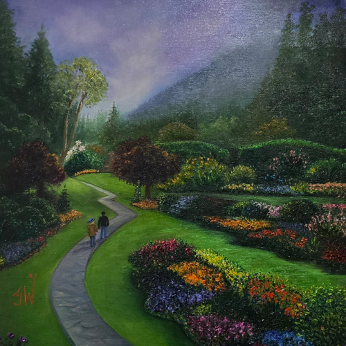 Two people walk along a winding stone path through a lush, vibrant garden toward a forested hillside at twilight.
