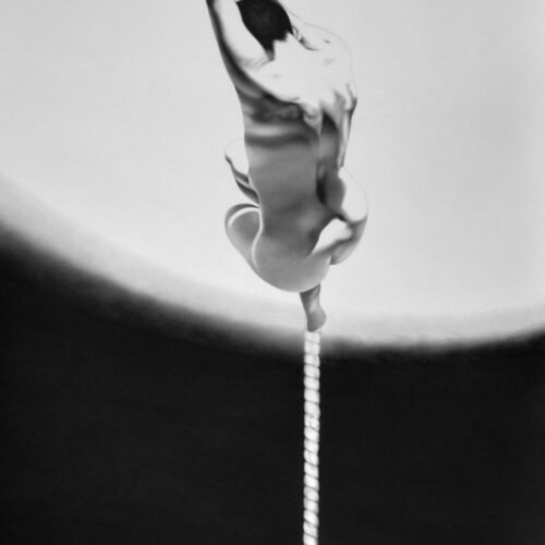 abstract black and white image showing liquid captured in mid air, shaped like a figure holding onto a vertical rope or string, with a blurry circular background.